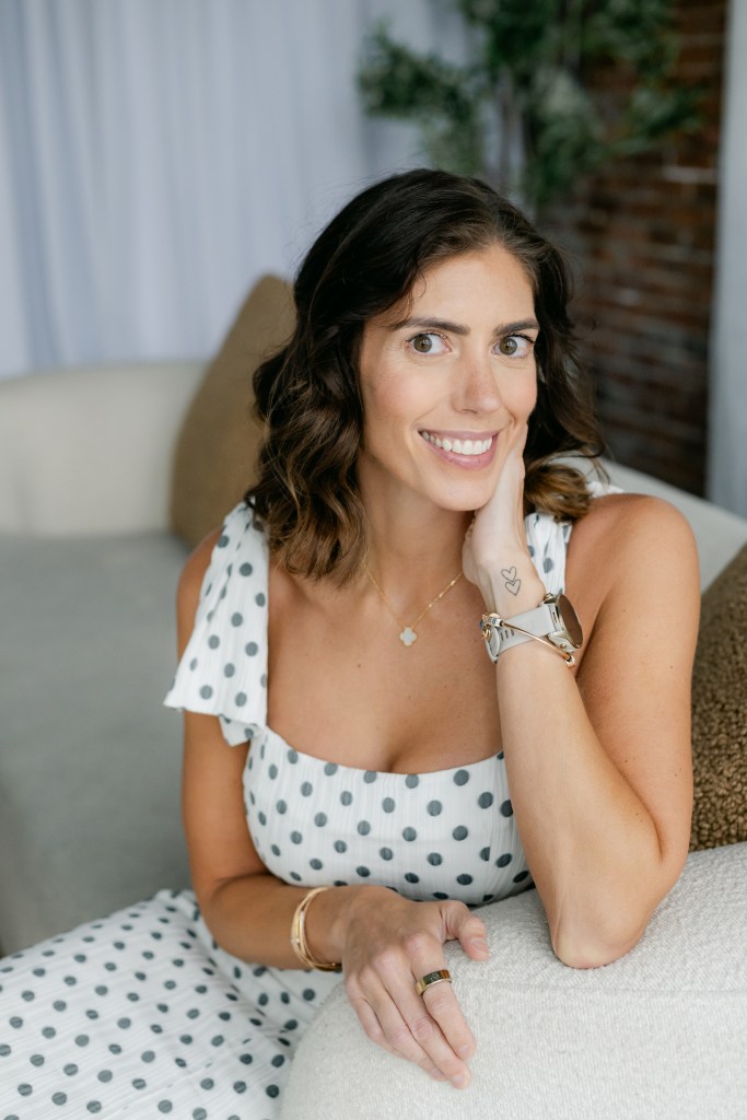 Courtney DuBois Shihabuddin smiling, seated on a sofa