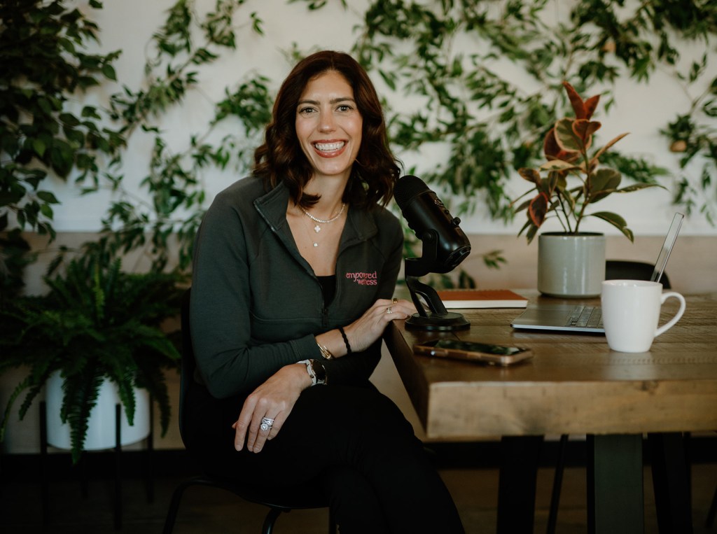 Courtney DuBois Shihabuddin at a desk with a podcast microphone and laptop